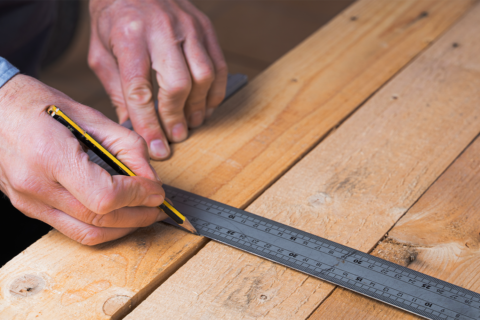 مردی در حال اندازه گیری برروی چوب